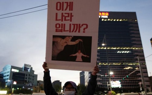 Người biểu tình ở Seoul, Hàn Quốc giơ bức tranh mô phỏng Tổng thống Park Geun-hye đang bị Choi Soon-sil điều khiển như một con rối - Ảnh: Getty.