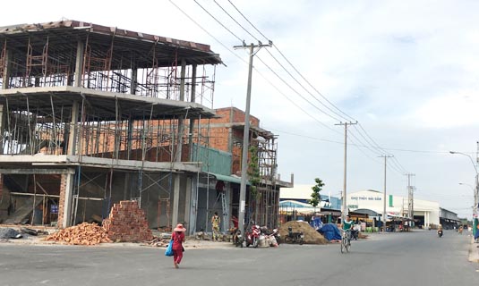 Nhiều tòa nhà đang mọc lên bên chợ đã hoạt động, trên đất chưa chuyển đổi mục đích sử dụng ở Khu thương mại dịch vụ và dân cư Mỹ Thới.