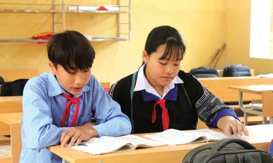 Em Sùng Thanh Tâm (bên phải) ngồi học bài dưới ánh sáng mới của lớp học.