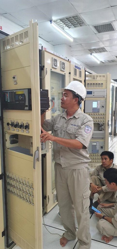 Anh Đặng Quốc Anh (đứng) đang làm việc trong Phòng Điều khiển Trung tâm thuộc Nhà máy Thủy điện An Khê